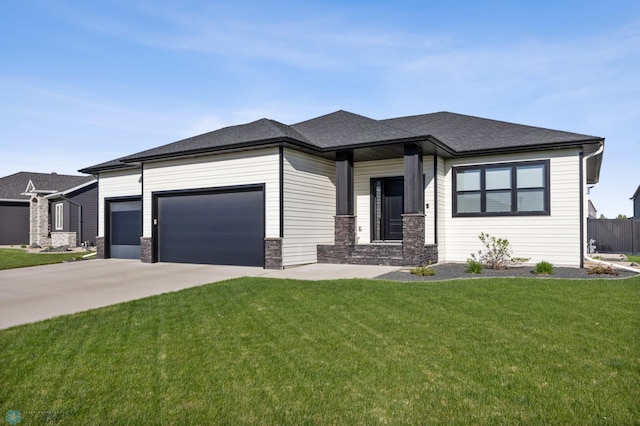 prairie-style home with a garage, concrete driveway, a front lawn, stone siding, and roof with shingles