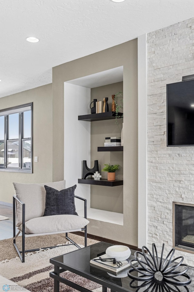 living room featuring a fireplace, a textured ceiling, and recessed lighting
