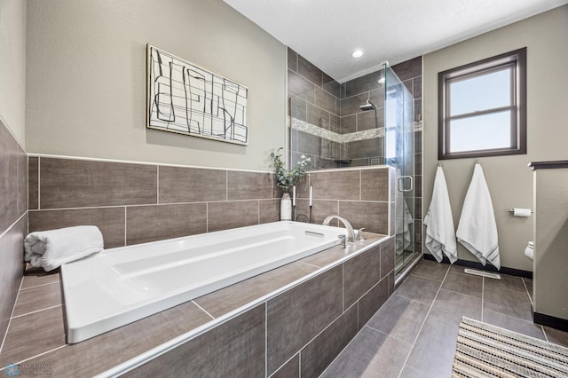 full bathroom featuring a stall shower, a garden tub, tile patterned floors, baseboards, and toilet
