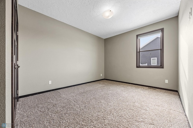 empty room with carpet, a textured ceiling, and baseboards