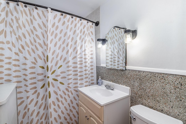 bathroom featuring vanity, tile walls, and toilet