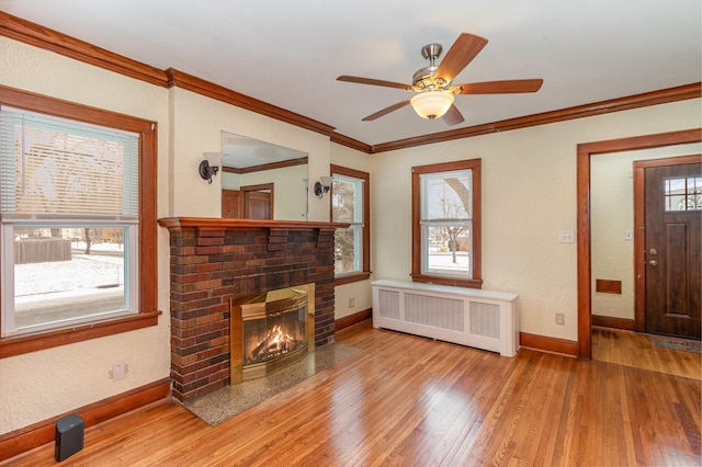 living room with ornamental molding, a fireplace, radiator, and light wood-type flooring