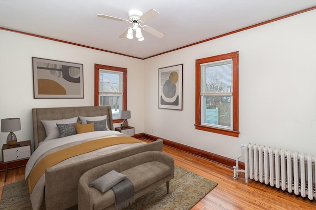 bedroom featuring crown molding, ceiling fan, radiator heating unit, and light wood-type flooring