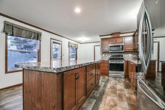 kitchen featuring light stone countertops, a kitchen island, dark hardwood / wood-style flooring, backsplash, and stainless steel appliances