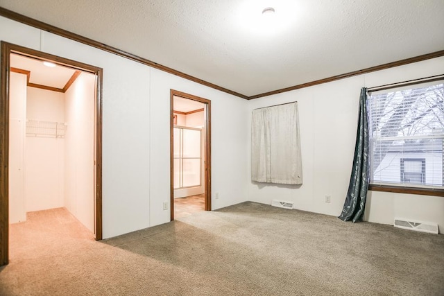 unfurnished bedroom with ornamental molding, light colored carpet, and a textured ceiling