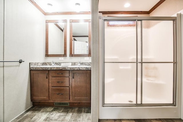 bathroom with hardwood / wood-style flooring, vanity, a shower with shower door, and ornamental molding