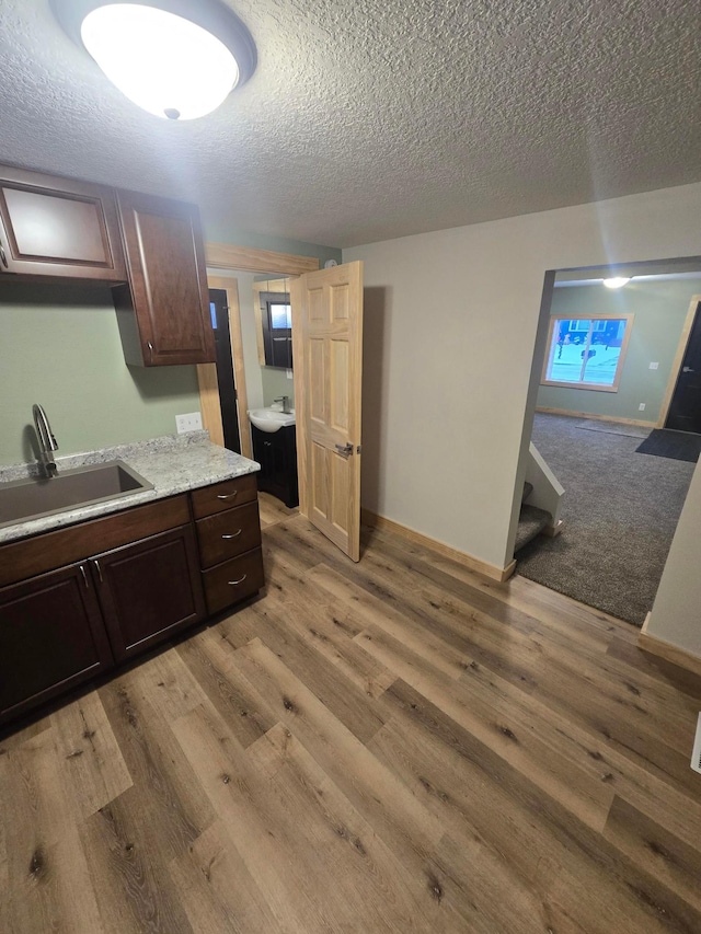 kitchen featuring a textured ceiling, sink, light hardwood / wood-style floors, and dark brown cabinetry