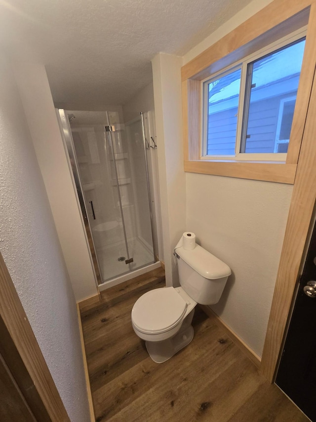 bathroom with toilet, wood-type flooring, walk in shower, and a textured ceiling
