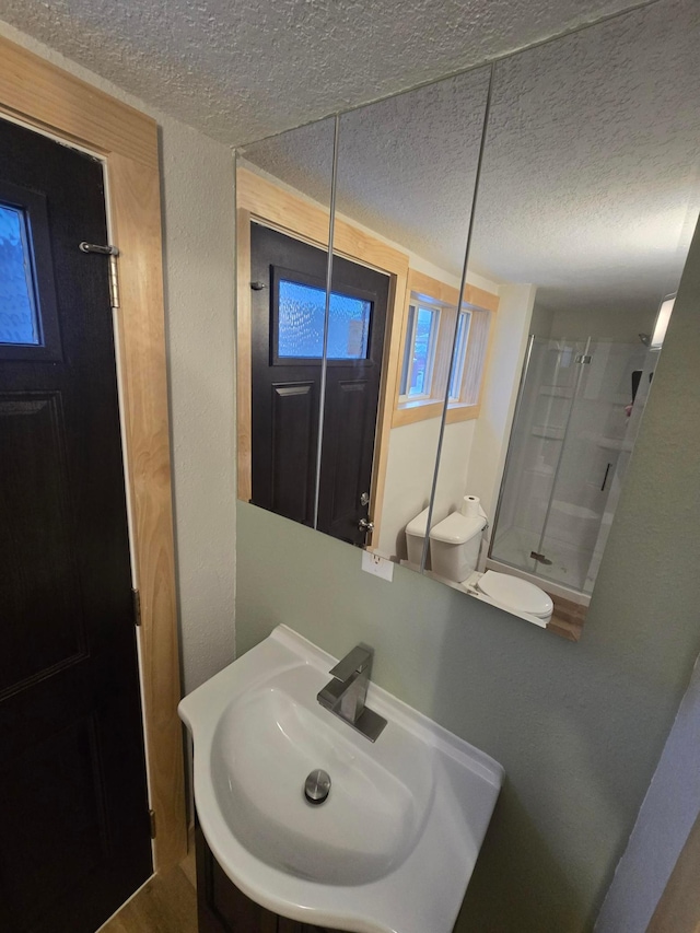 bathroom with a textured ceiling, toilet, a shower, and vanity
