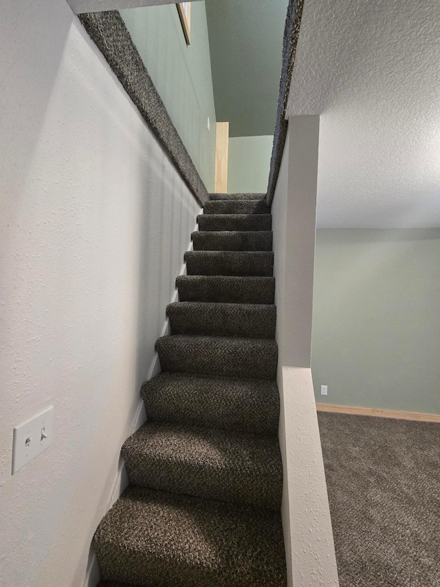 staircase featuring a textured ceiling and carpet floors