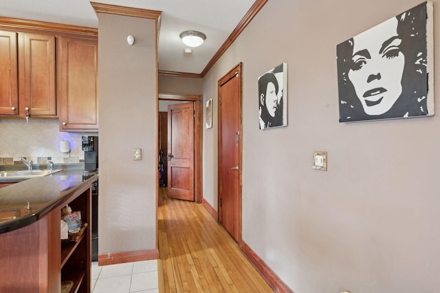 hallway featuring sink, ornamental molding, and light wood-type flooring