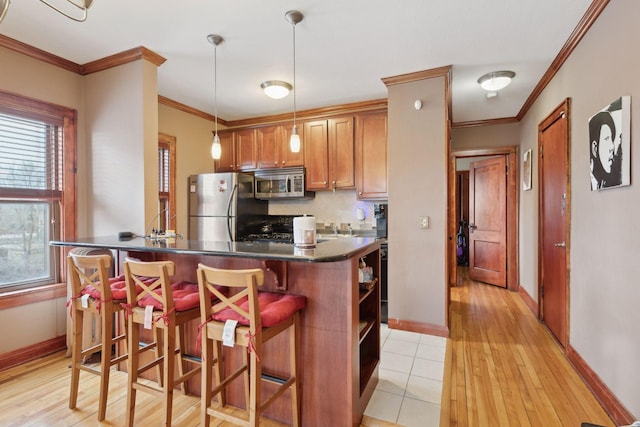 kitchen with stainless steel appliances, crown molding, pendant lighting, and a kitchen bar