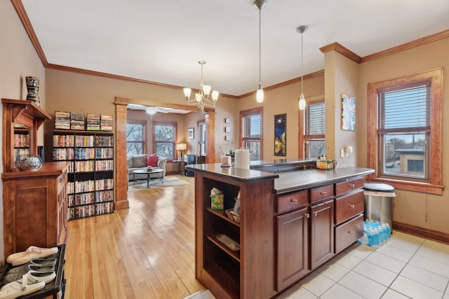 kitchen with crown molding, hanging light fixtures, light hardwood / wood-style floors, a kitchen island, and a chandelier