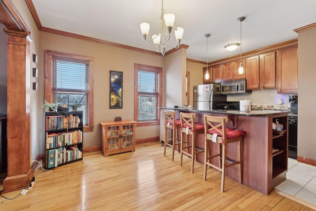 kitchen featuring appliances with stainless steel finishes, a breakfast bar area, light wood-type flooring, and decorative light fixtures