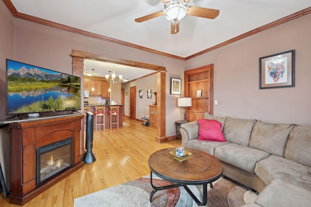 living room featuring ornamental molding, ceiling fan with notable chandelier, and light hardwood / wood-style flooring