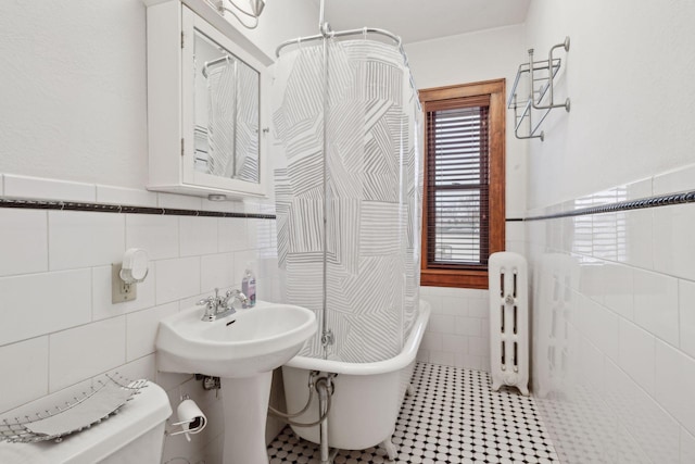 bathroom featuring a tub, tile walls, and toilet