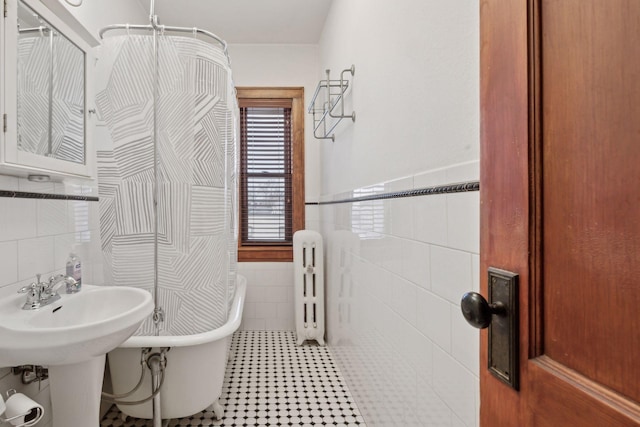 bathroom featuring tile walls, radiator, tile patterned floors, and a tub to relax in