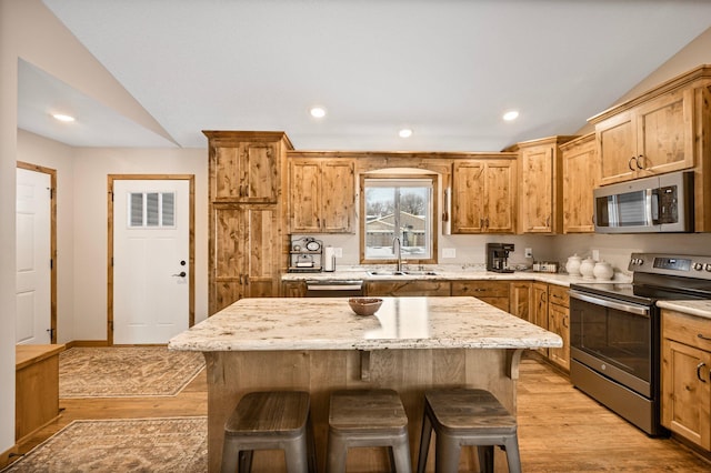 kitchen featuring stainless steel appliances, a kitchen island, sink, and a kitchen breakfast bar