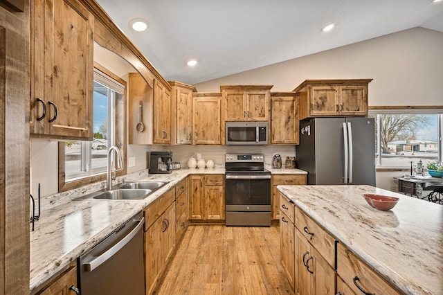 kitchen featuring vaulted ceiling, stainless steel appliances, sink, and light wood-type flooring