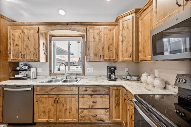 kitchen featuring stainless steel appliances, light stone countertops, and sink