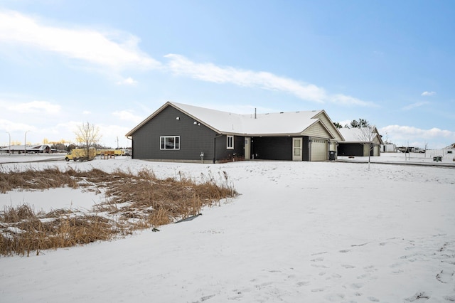 snow covered back of property with a garage