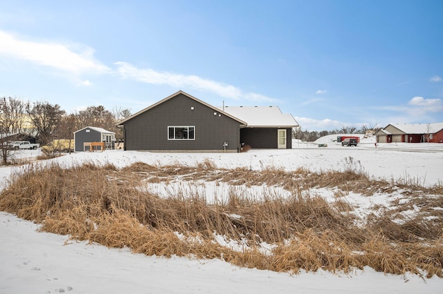 snow covered house featuring a shed