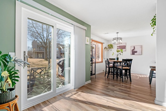 dining area featuring light wood-style flooring, baseboards, and an inviting chandelier