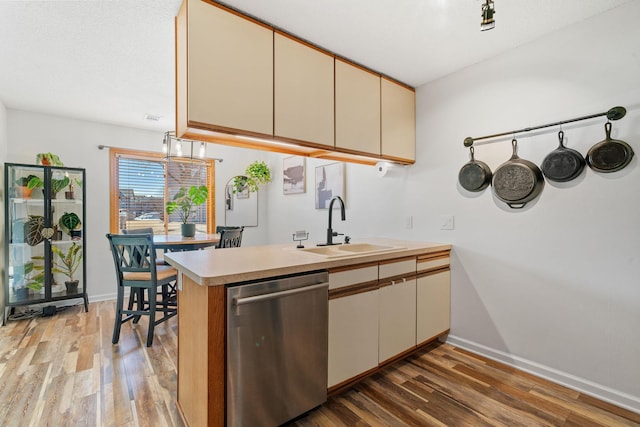 kitchen featuring dishwasher, light countertops, cream cabinetry, and a sink