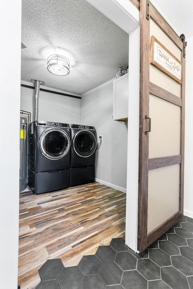 laundry room with gas water heater, washer and clothes dryer, a barn door, a textured ceiling, and laundry area