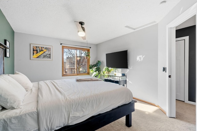 bedroom with a ceiling fan, light colored carpet, a textured ceiling, and baseboards