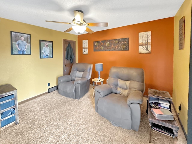 sitting room with ceiling fan, a textured ceiling, and carpet flooring