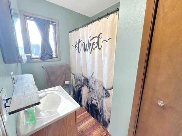 bathroom featuring vanity, a textured ceiling, and curtained shower