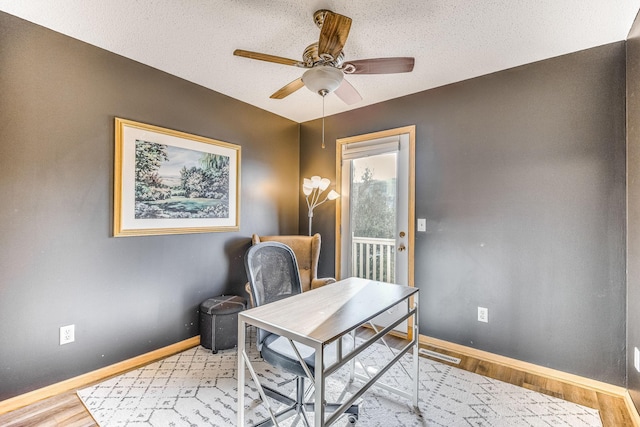 home office featuring ceiling fan, light wood-type flooring, and a textured ceiling