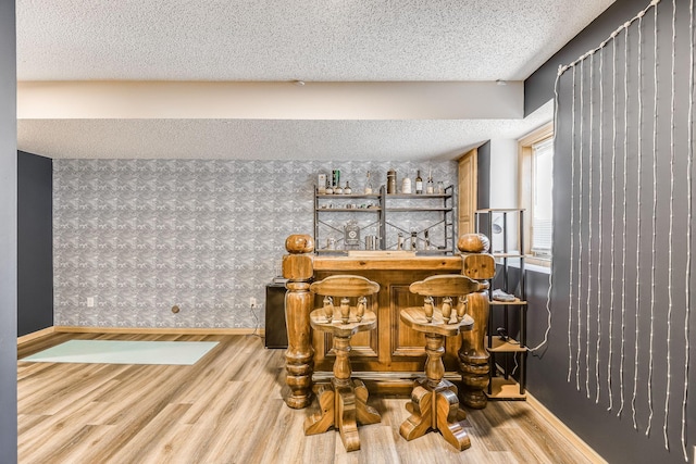 dining area with bar, a textured ceiling, and hardwood / wood-style flooring