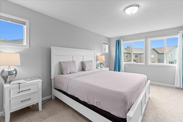 bedroom with light carpet, a textured ceiling, and baseboards