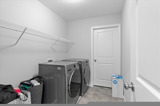 clothes washing area featuring laundry area, a textured ceiling, and washing machine and clothes dryer