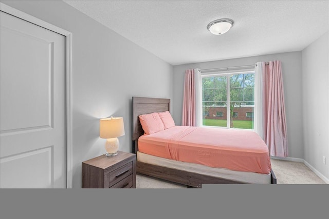 bedroom featuring light carpet, a textured ceiling, and baseboards