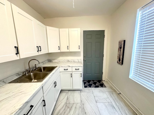 kitchen featuring white cabinets, light stone countertops, and sink