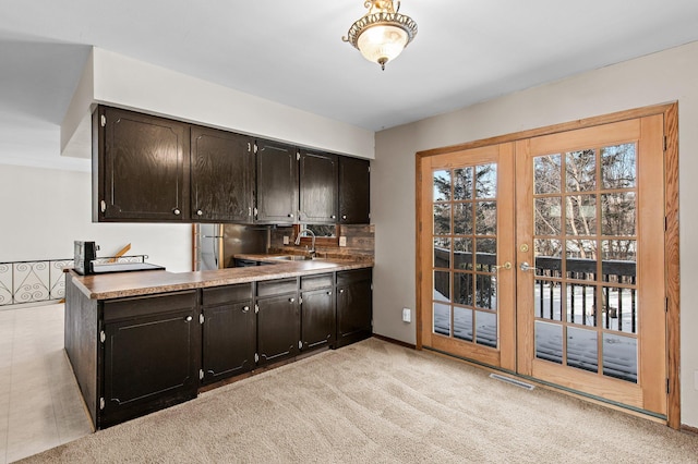 kitchen with sink, dark brown cabinetry, french doors, and light carpet