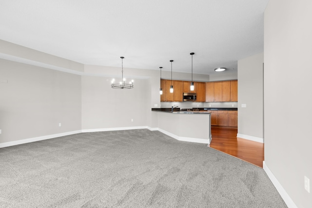 kitchen featuring kitchen peninsula, pendant lighting, carpet, and a notable chandelier