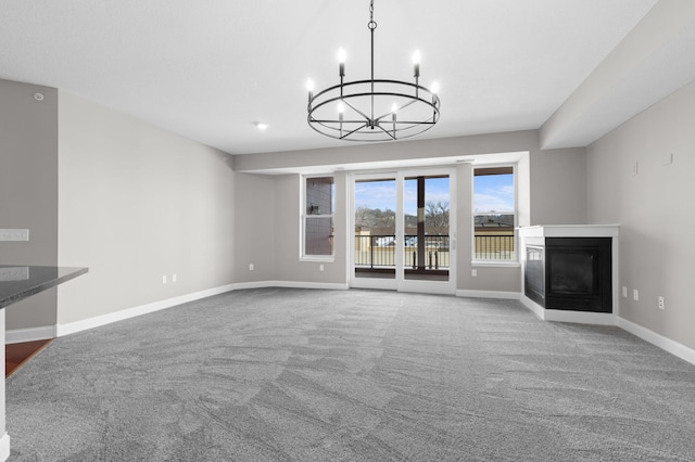 unfurnished living room with a multi sided fireplace, carpet floors, and a notable chandelier