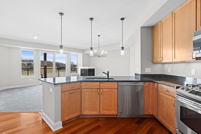 kitchen with pendant lighting, appliances with stainless steel finishes, dark colored carpet, sink, and kitchen peninsula