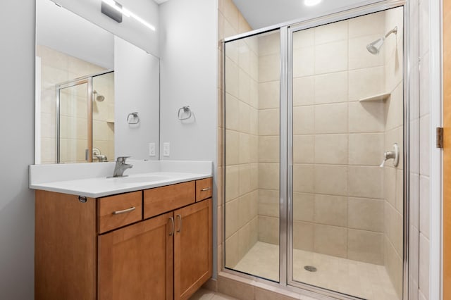 bathroom featuring a shower with shower door and vanity