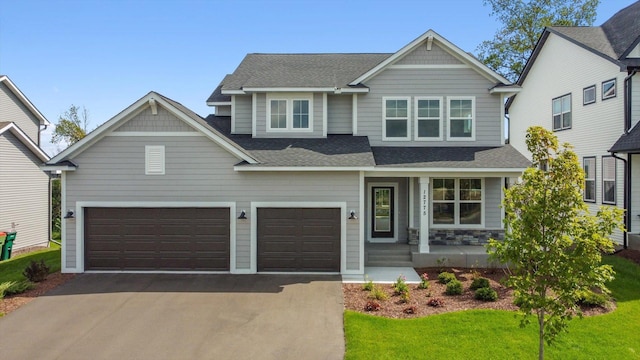 craftsman inspired home with a garage, a front yard, and a porch