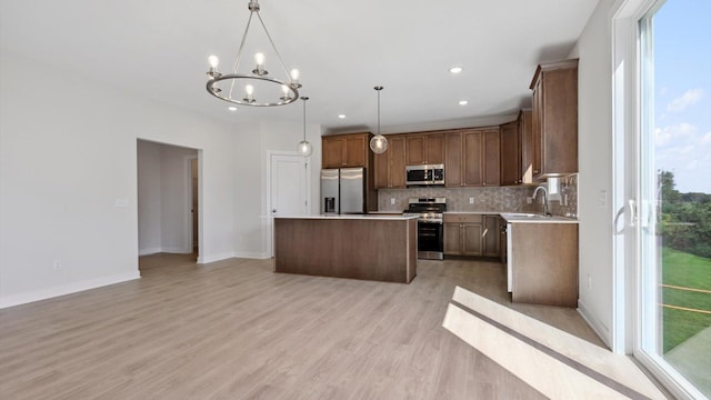 kitchen featuring a center island, decorative light fixtures, stainless steel appliances, light hardwood / wood-style floors, and sink