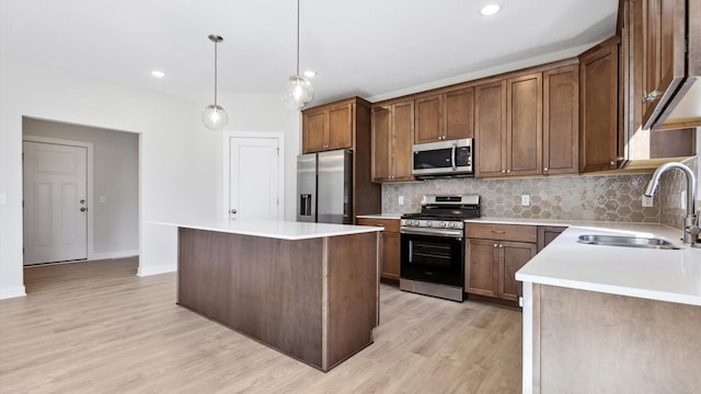 kitchen with pendant lighting, sink, light wood-type flooring, a center island, and stainless steel appliances