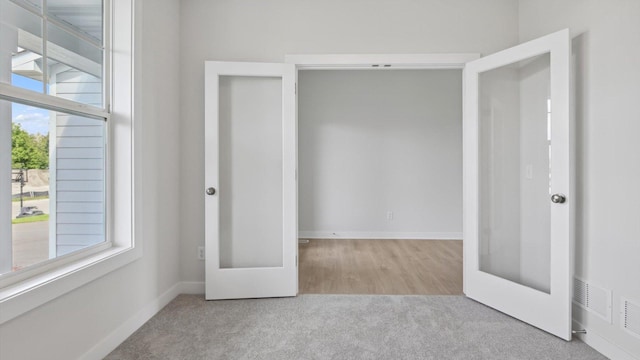 unfurnished bedroom with light colored carpet and french doors