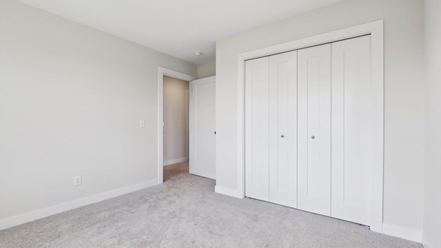 unfurnished bedroom with light carpet and a closet