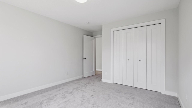 unfurnished bedroom with a closet and light colored carpet