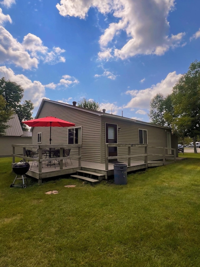 rear view of house with a wooden deck and a lawn